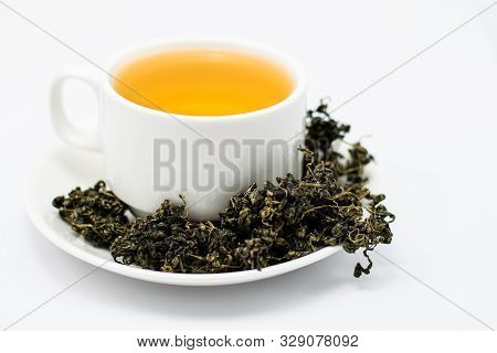 Dry Gynostemma Pentaphyllum Leaf With Tea Brewed In A White Cup On White Blackground
