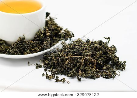 Dry Gynostemma Pentaphyllum Leaf With Tea Brewed In A White Cup On White Blackground
