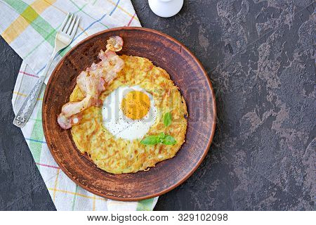 Potato Hash Brown With Egg And Bacon On A Brown Clay Plate On A Dark Concrete Background. American C