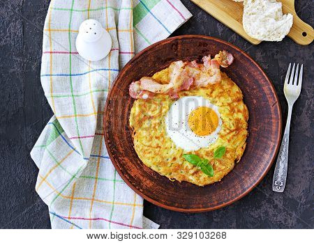 Potato Hash Brown With Egg And Bacon On A Brown Clay Plate On A Dark Concrete Background. American C