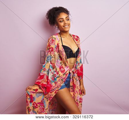 Young beautiful african american woman on vacation standing wearing bikini and colorful caftan