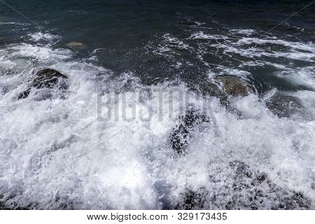 Sea Surf On The Beach With Black Volkanic Sand And Stones.
