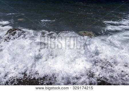 Sea Surf On The Beach With Black Volkanic Sand And Stones.