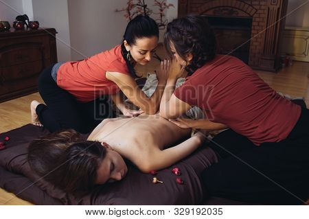 Two Massage Therapist Doing Healing Massage, Massage In Four Hands. Woman Enjoying In Relaxing Massa