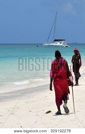 Kendwa, Zanzibar - October 3, 2019: Man From Masai Tribe In Traditional Dress Walks Along Kendwa Bea