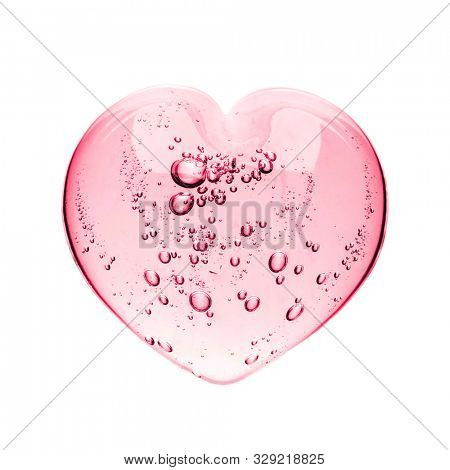 Pink serum gel, heart shape puddle isolated on white backdrop, top view. Squeezed transparent care gel with bubbles close up, macro isolated on white background.