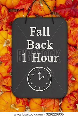 Fall Back 1 Hour Time Change Message On A Chalkboard Sign On Pumpkins With Fall Leaves And A Straw H