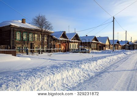 Snow-covered Village Street In Winter. View Of The Traditional Wooden Houses On A Sunny Winter Day. 