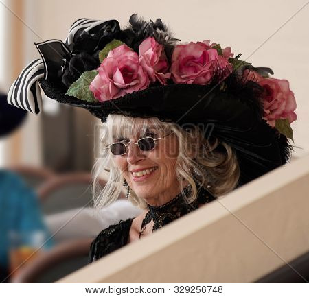 Portrait Of An Attractive Senior In Period Dress, Including A Very Elaborate Feathered And Flowered 