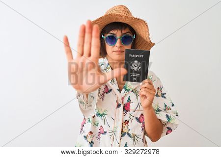 Tourist woman on vacation holding USA United States passport over isolated white background with open hand doing stop sign with serious and confident expression, defense gesture