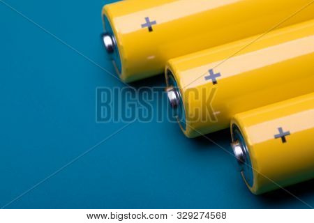 Close up shot of yellow AA alkaline or rechargeable NiMH batteries on blue background, shallow focus