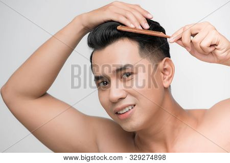 Beauty, Grooming And People Concept - Smiling Young Man Brushing Hair With Comb Over White Backgroun