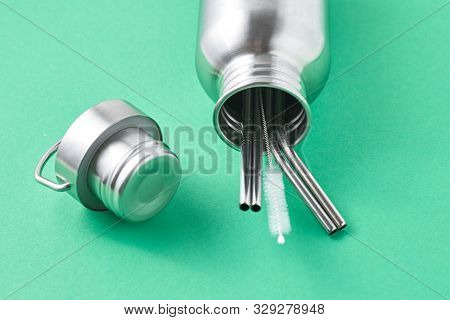 Reusable Plastic Free Items On Green Background. Top View Of Aluminun Bottle And Metal Tubes. Zero W