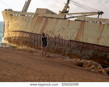 Silhouette Of Girl Taking A Photo On Sunset. Old Ship On The Mediterranean Sea Background. The Old E
