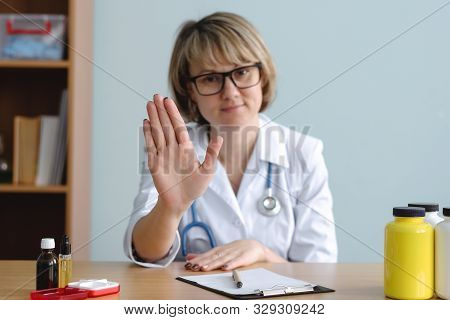 Woman A Doctor Is Showing A Stop Gesture By Her Hand. No Panic. Do Not Worry Concept. Denial In Medi
