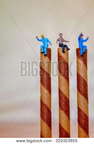 construction workers, conceptual with miniature plastic people in of high wafer sticks