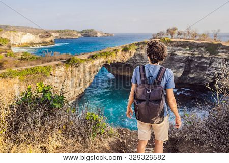Young Man Tourist Near Broken Beach In Nusa Penida, Indonesia Angels Billabong Beach. Popular Touris