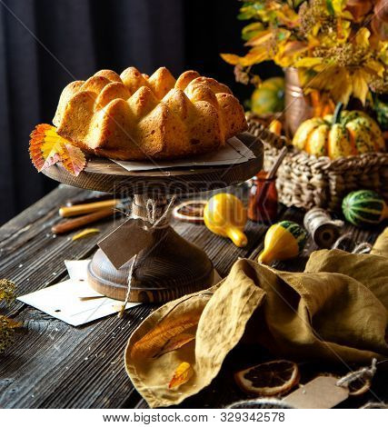 Homemade Tasty Baked Bundt Pumpkin Cake On Wooden Cake Stand On Rustic Table With Assorted Small Pum