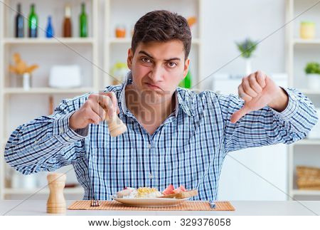 Young husband eating tasteless food at home for lunch