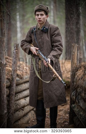 A Soldier Of World War Ii Is Standing In The Trench With A Rifle In Hands