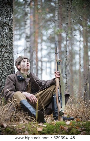 A Soldier Of World War Ii Is Sitting Near The Tree And Looking Up