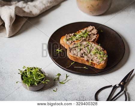 Two Toasts Chicken Rillettes (pate) On White Bread With Sprouts On Dark Wood Plate On A Light Backgr