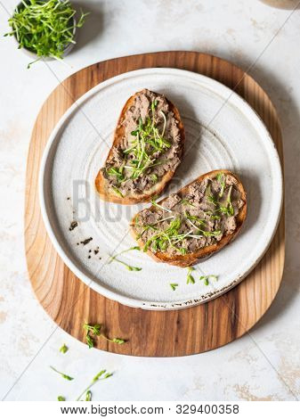Two Toasts Chicken Rillettes (pate) On White Bread With Sprouts On White Plate On A Wood Cutting Boa