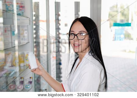 Pharmacy And Apothecary-seller. A Bespectacled Pharmacist Pulls Drugs From A Display Case And Smiles