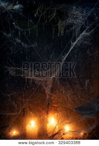 Candlelight in terrible darkness. A spooky web in an old window. Halloween Party Background