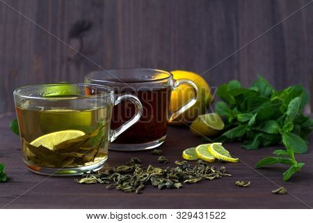 Healthy Lifestyle. Cups Of Green And Black Tea With Lemon And Leaves Of Green Mint On Wooden Backgro