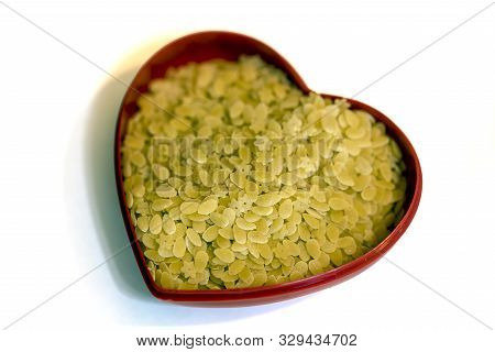 Little Small And Starry Italian Pasta Inside A Heart-shaped Container, Isolated On White Background.