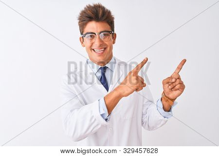 Young handsome sciencist man wearing glasses and coat over isolated white background smiling and looking at the camera pointing with two hands and fingers to the side.