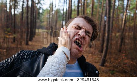 A Womans Hand Hits A Mans Face In The Autumn Forest. An Emotional Male Is Getting Slapped In Face, W