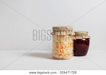 Homemade Sauerkraut With Carrots And Cabbage Salad With Beets In A Glass Jar On A White Wooden Backg