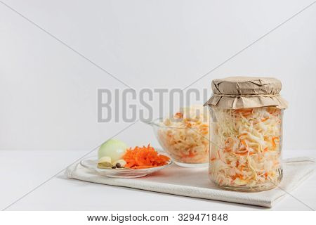 Homemade Sauerkraut With Carrots In A Glass Jar And Bowl On A White Wooden Background. Fermented Foo