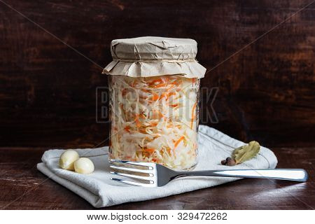 Homemade Sauerkraut With Carrots In A Glass Jar On A Dark Wooden Background. Fermented Food. Marinat
