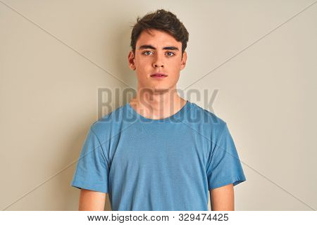 Teenager boy wearing casual t-shirt standing over isolated background with serious expression on face. Simple and natural looking at the camera.