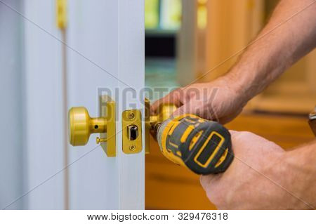 Closeup Of A Professional Locksmith Installing Or New Lock On A House Door Handle With Screwdriver