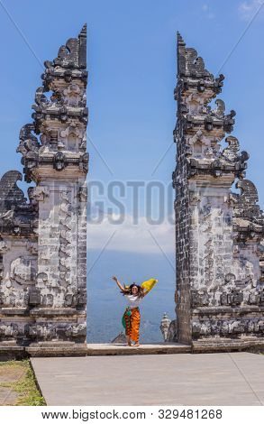 BALI, INDONESIA - SEPTEMBER 17, 2019: Happy woman at the entrance temple of Pura Penataran Agung Lempuyang. In Bali, Indonesia