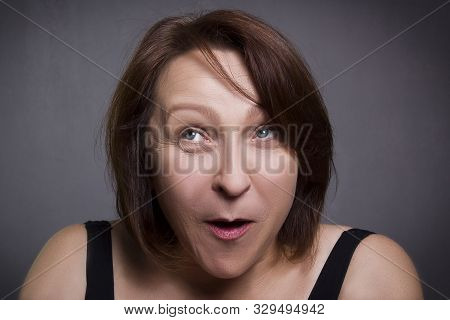 Woman Grimaces In Front Of Camera On Black Background
