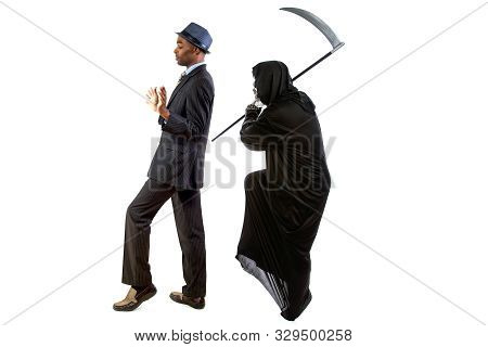 Man In A Grim Reaper Halloween Ghost Costume Having Fun And Scaring A Grown Businessman In A Suit.  