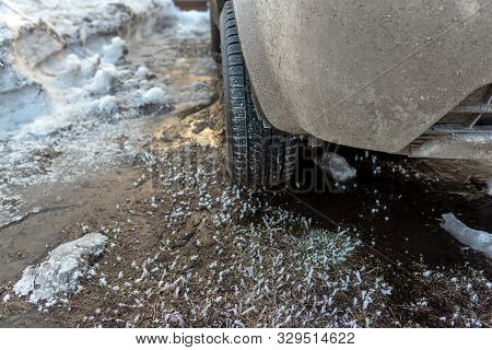 Winter Tire With Spikes On The Front Of The Off-road Car Stands On Winter Ice With Snow And Reflecti