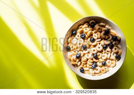 Healthy Breakfast With Cereal And Blueberry.bowl With Healthy Cornflakes, Milk And Berries On Yellow