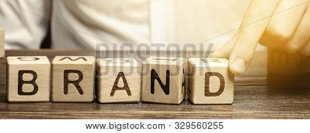 Businessman Puts Wooden Blocks With The Word Brand. Business, Marketing, And Advertising. Name, Term