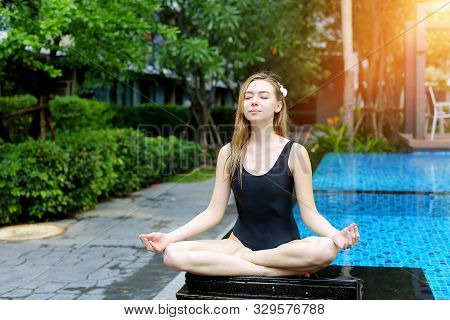 Mentaly Strong Woman Sitting In Lotus Position, Doing Yoga By The Pool On A Sunny Day