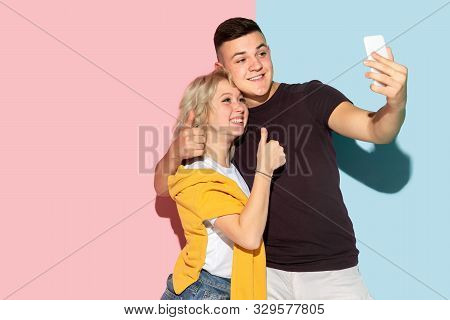 Young Emotional Man And Woman In Bright Casual Clothes Posing On Pink And Blue Background. Concept O