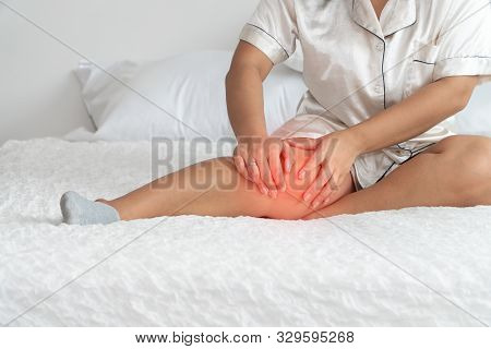Overweight Woman Sitting On The Bed And Catching The Knees Because Of The Pain Caused By Overweight 