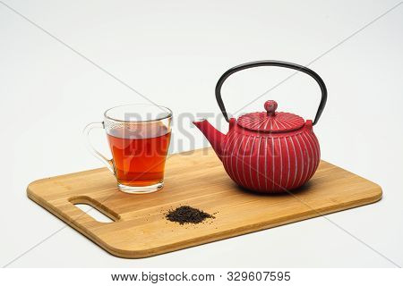 Cast-iron Teapot On A Wooden Board And A Glass Cup With Hot Tea On A White Background.