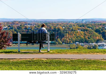 Quebec City, Ca - 5 October 2019 - Woman Sitting On A Bench Looking At Levis City From Plains Of Abr