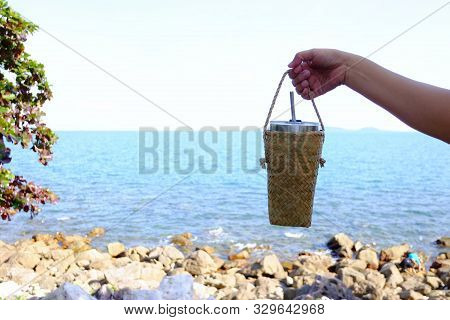 A Female Hand Holding A Recycled Glass Of Drinking Water With Sea View For An Environment Clening Co